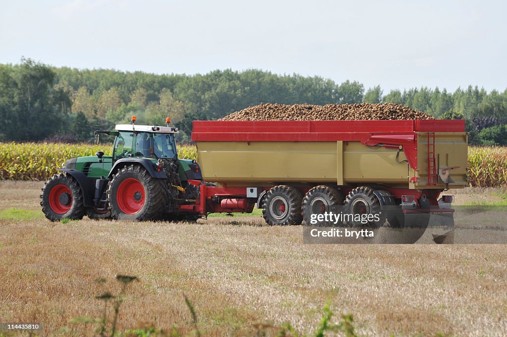 Tractor pulling a loaded farm trailer across a harvested field